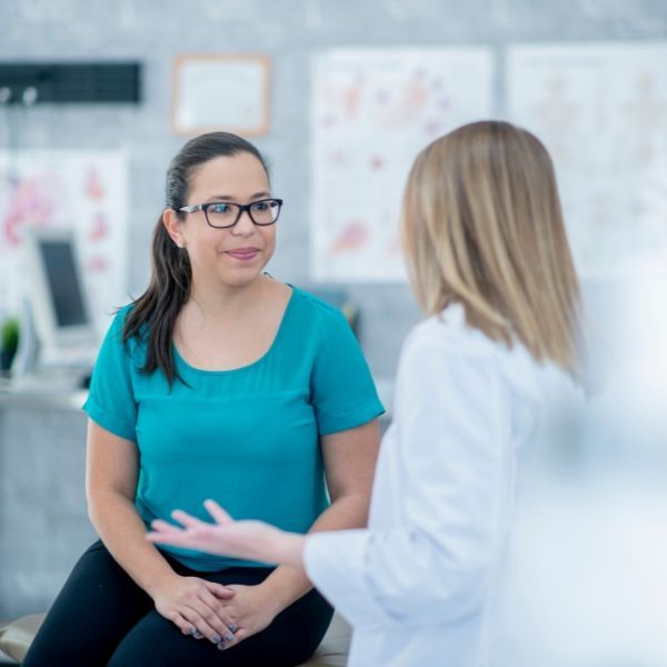 A woman is sitting and talking to a doctor about peptide therapy.