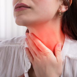 a woman is holding her neck in pain because of a sore throat .