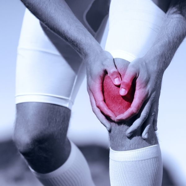 A person is holding their knee in pain due to a sports injury