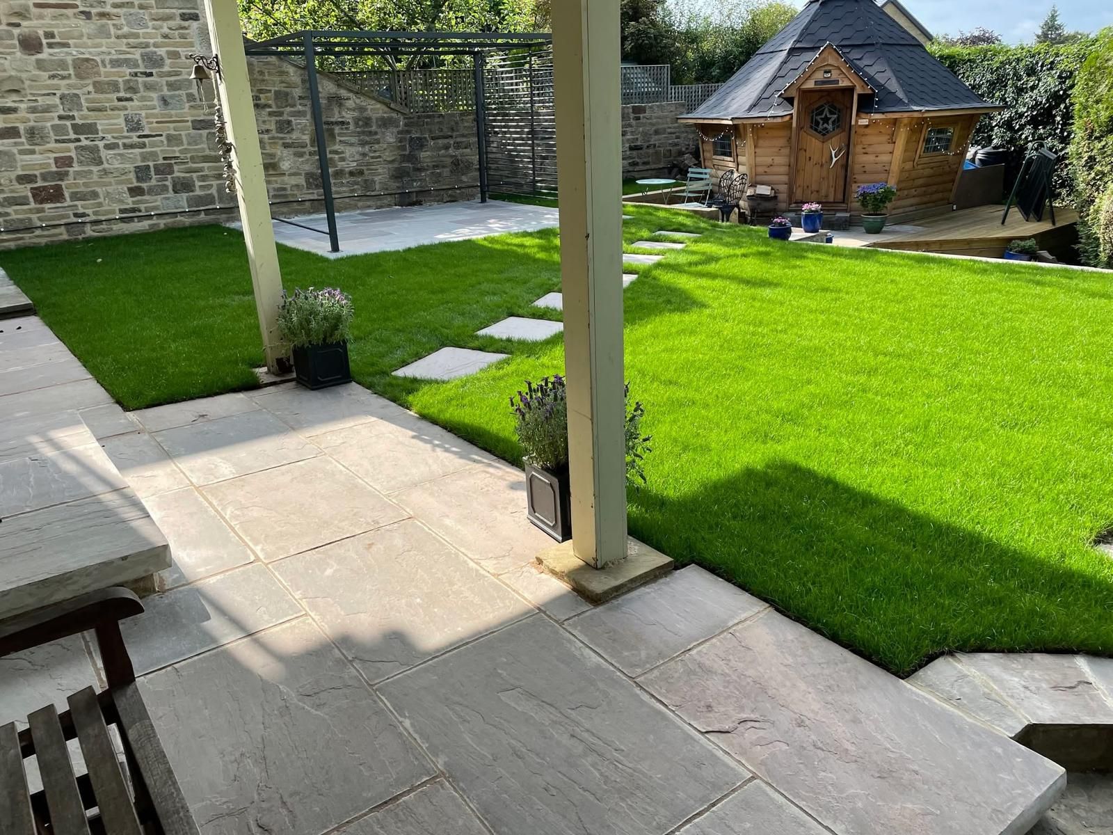 Backyard with patio, green lawn, wooden gazebo, and small wooden cabin.