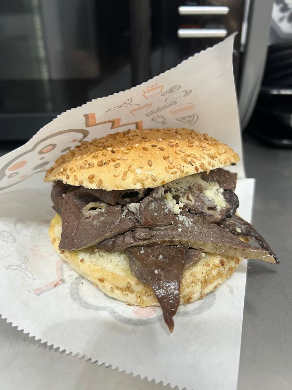 Panino con semi di sesamo, ripieno di un cheeseburger spesso e formaggio fuso, avvolto in una sfoglia bianca, in un'auto.