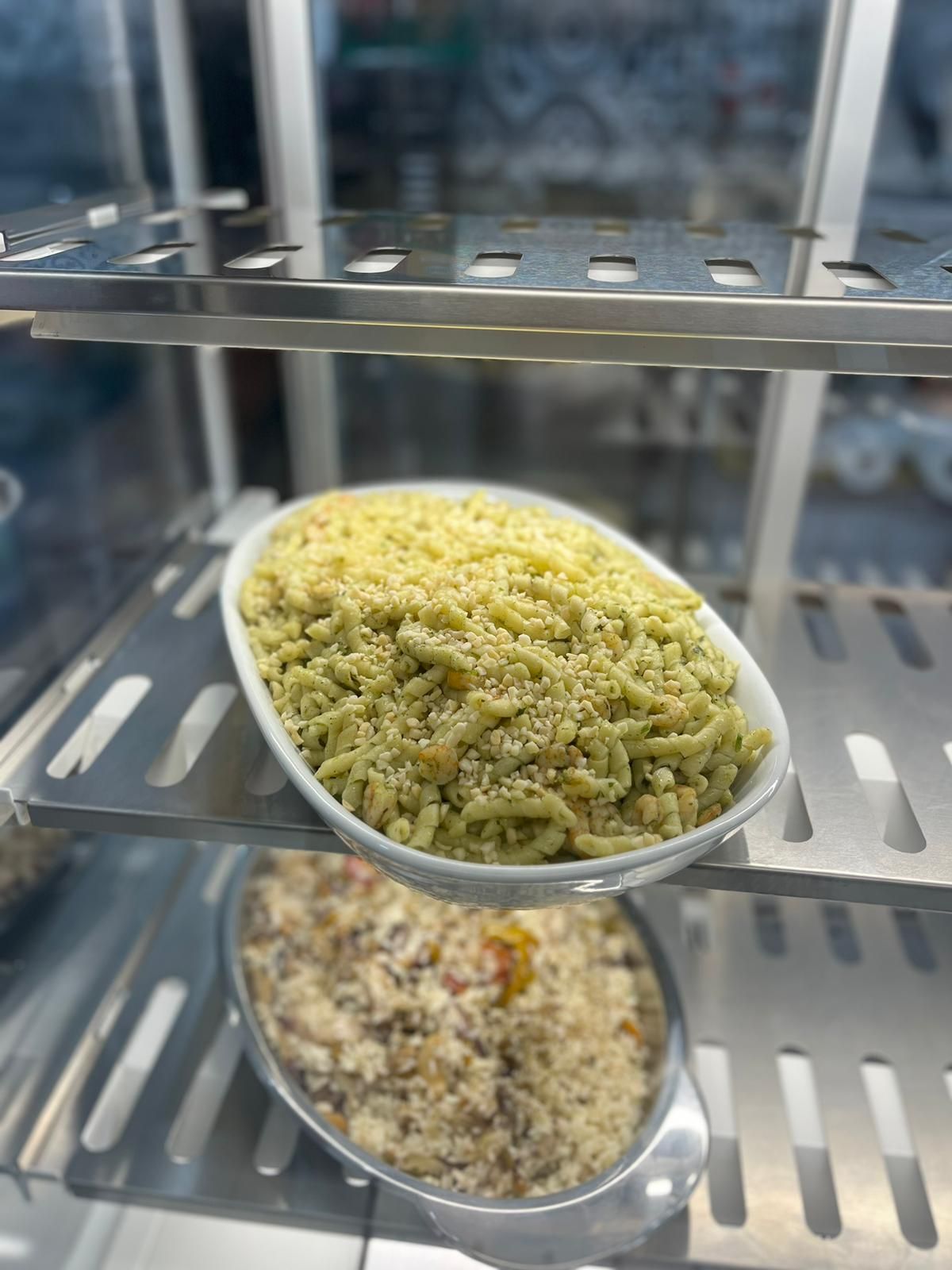 Due ciotole di cereali o insalata su ripiani metallici all'interno di un espositore refrigerato.
