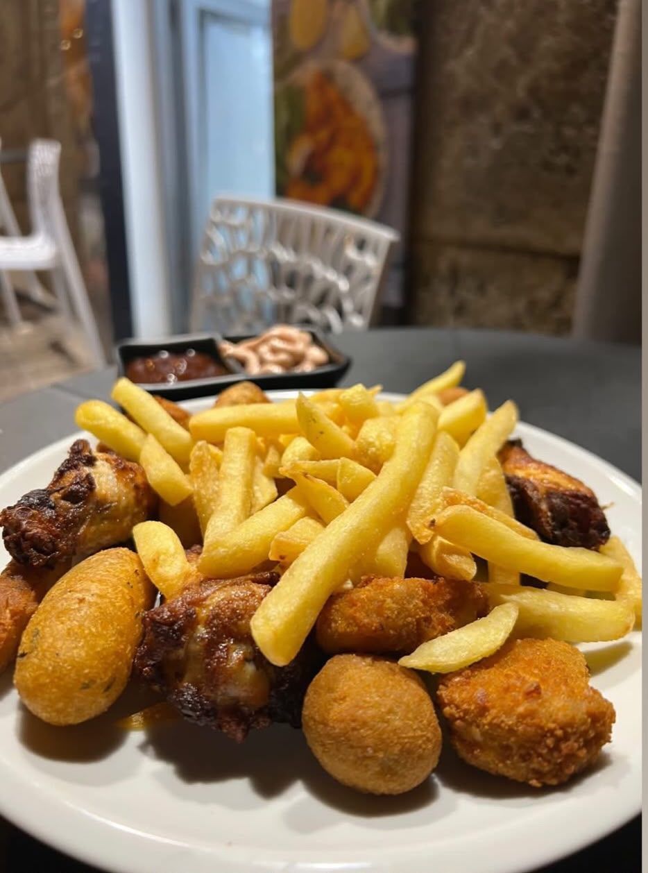 Antipasti fritti e patatine fritte su un piatto a un tavolo all'aperto.