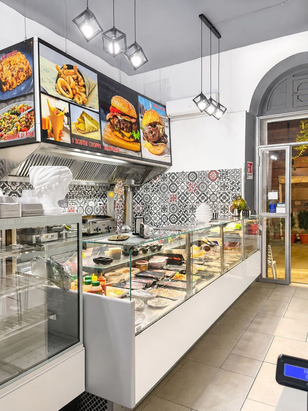 Banco gastronomia moderno con pasticcini e panini in un luminoso locale dai colori cangianti.