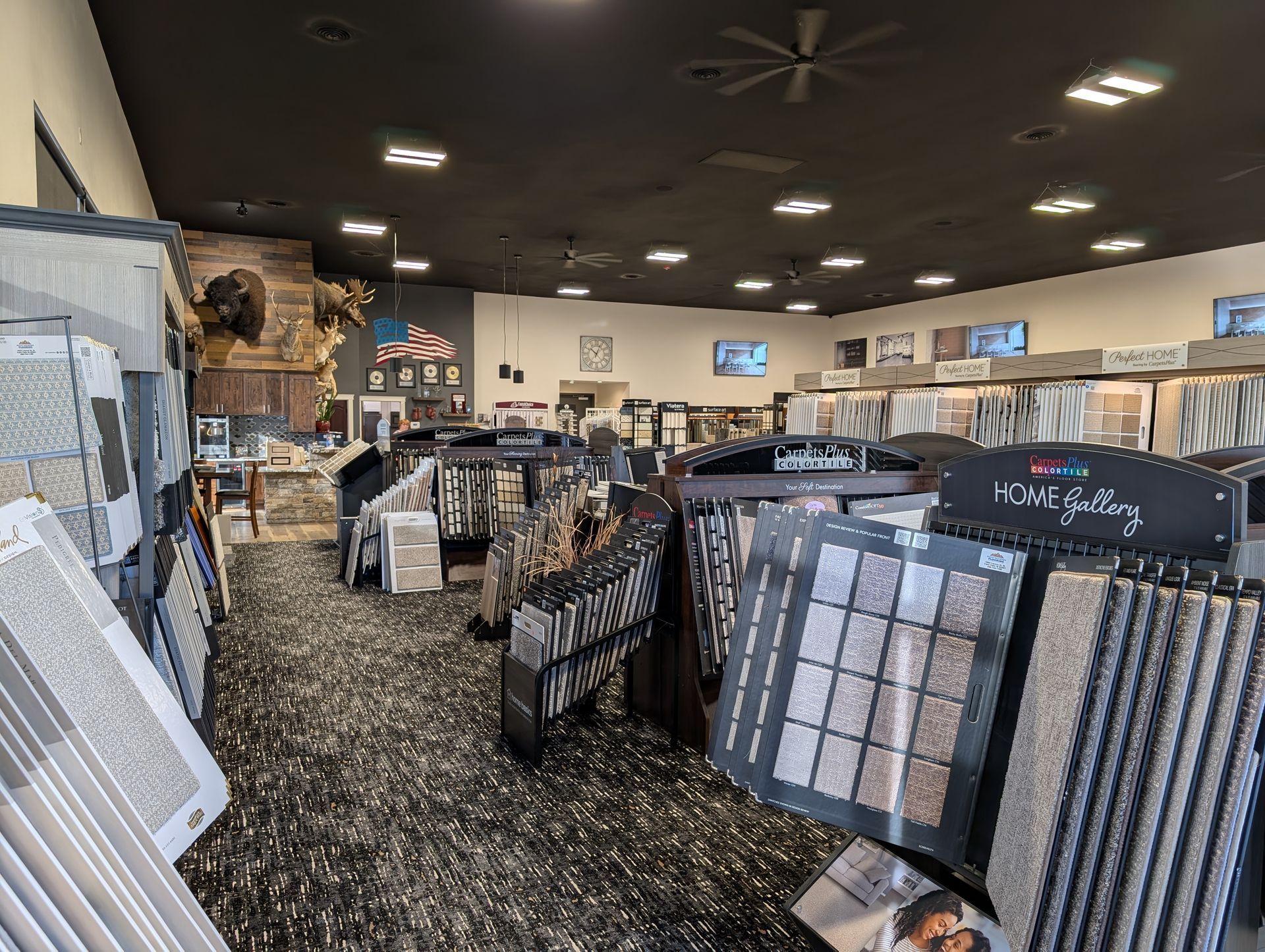 A large room filled with lots of carpets and a ceiling fan.