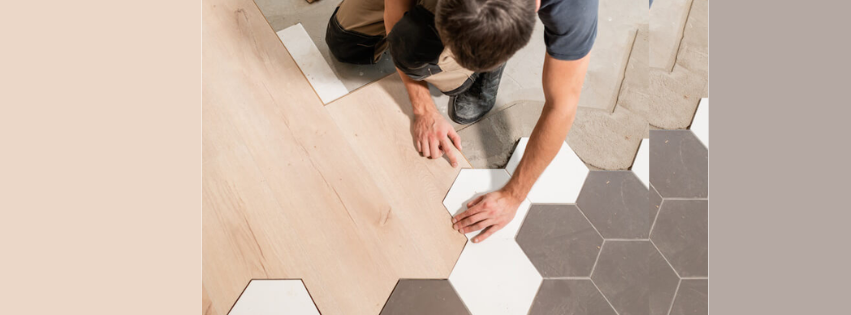 A man is installing a wooden floor with hexagonal tiles.