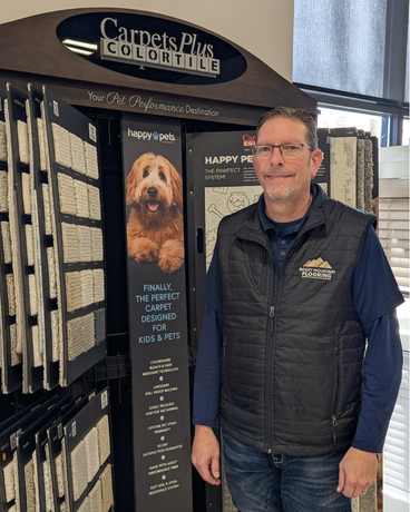 A man is standing in front of a carpet display in a store.