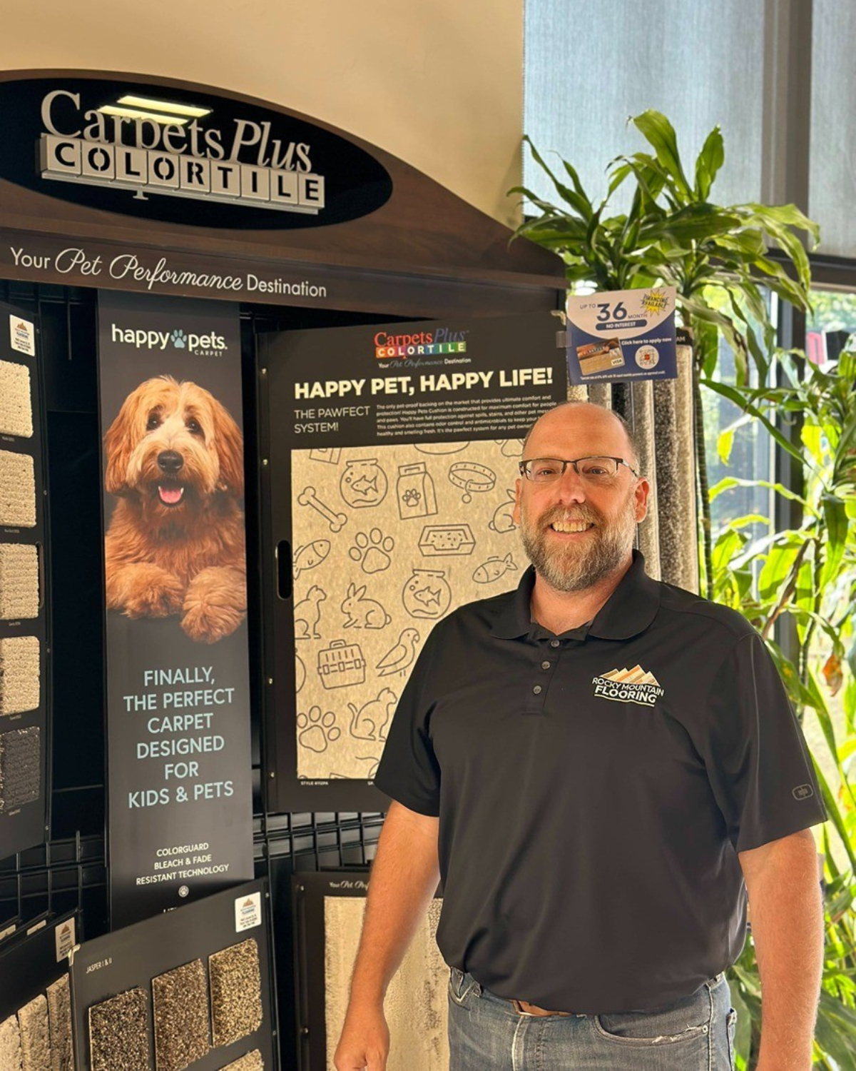 A man is standing in front of a carpets plus color tile display.