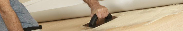 A person is cleaning a mattress with a vacuum cleaner.