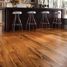 A kitchen with hardwood floors and stools around the island.