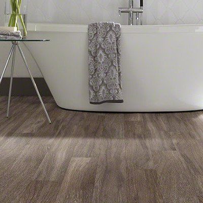 A bathroom with a bathtub and a wooden floor.