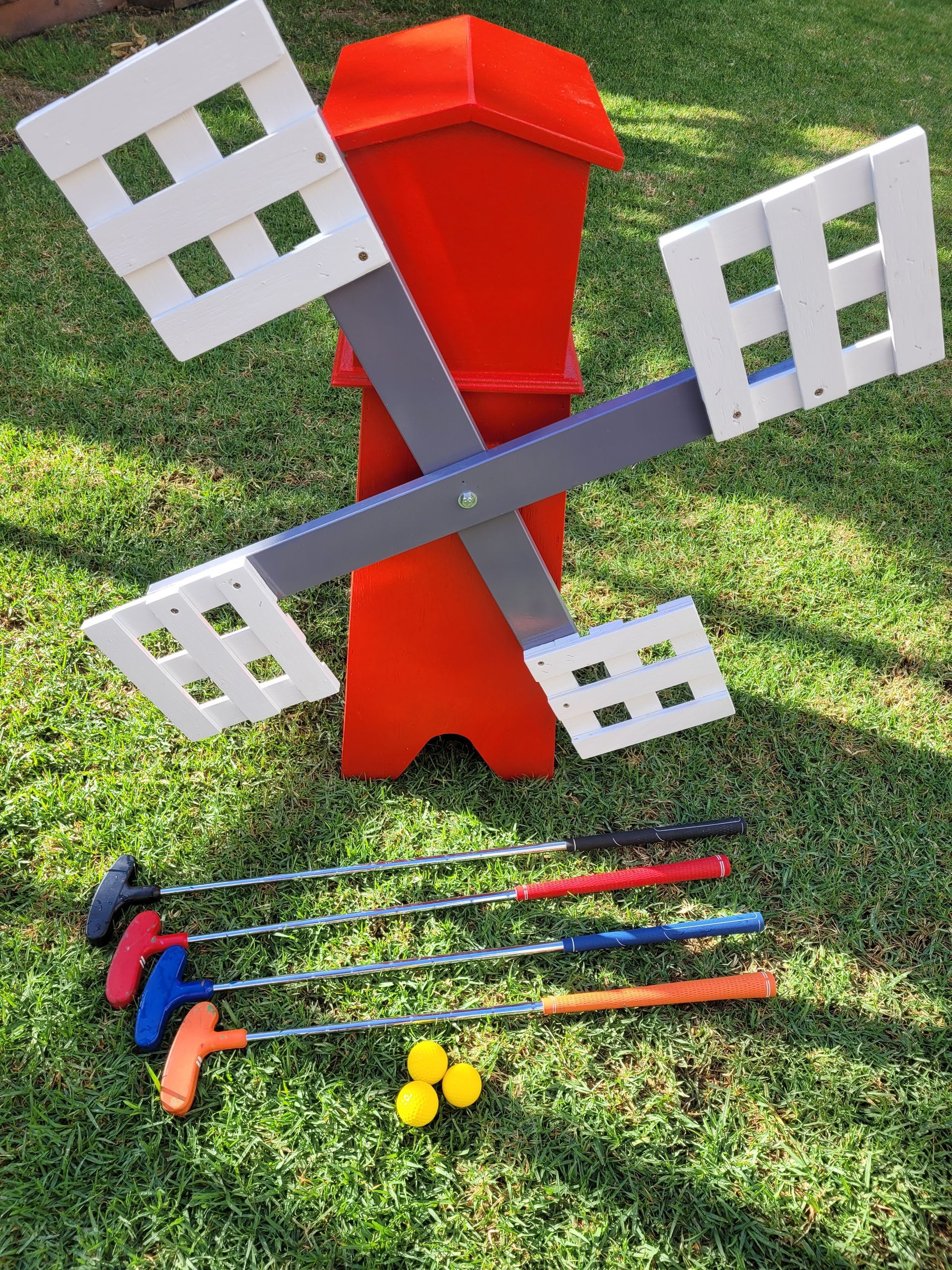Miniature golf game setup with red windmill and putters.