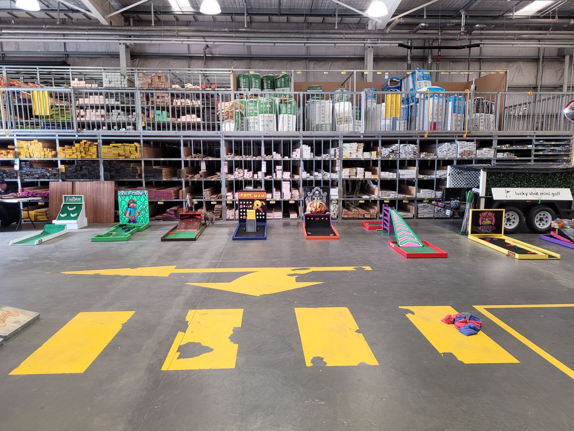 Sunset over an outdoor event with a child playing on a colorful mat. Large building and crowd in background.