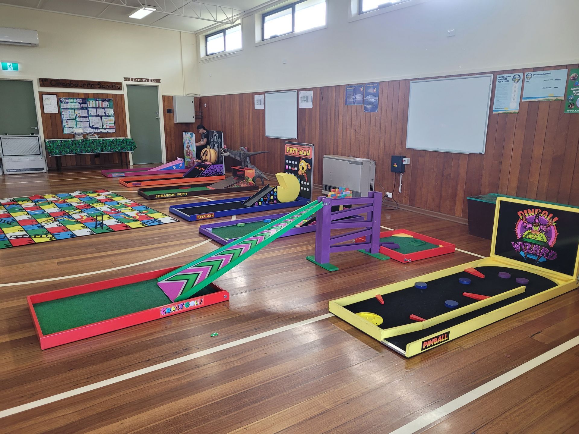 Indoor mini golf course setup on a wooden floor, featuring various colorful obstacles and ramps.