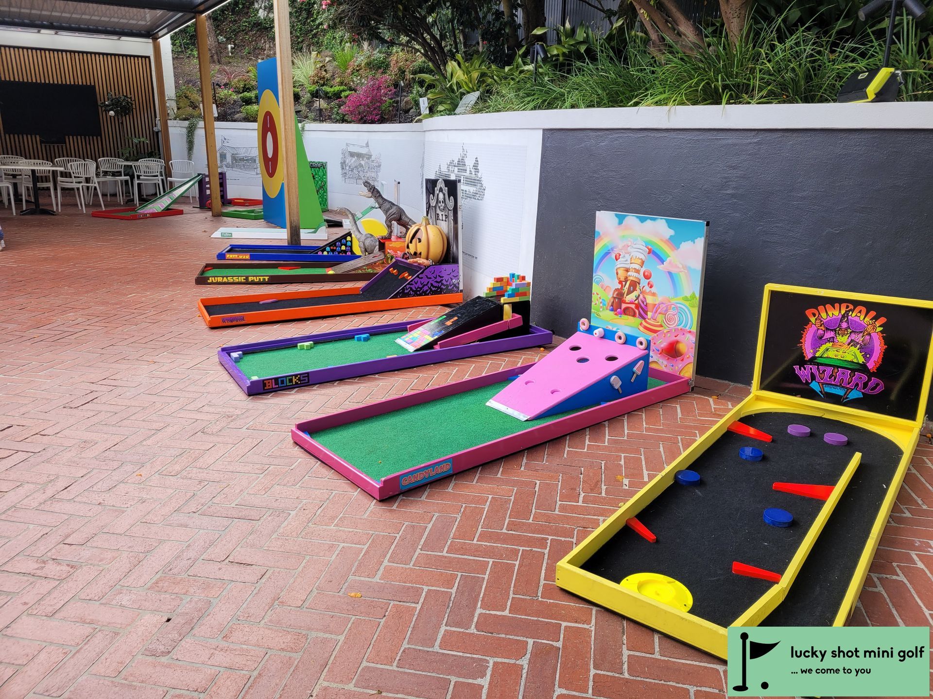 Mini golf course with colorful obstacles on a brick patio.