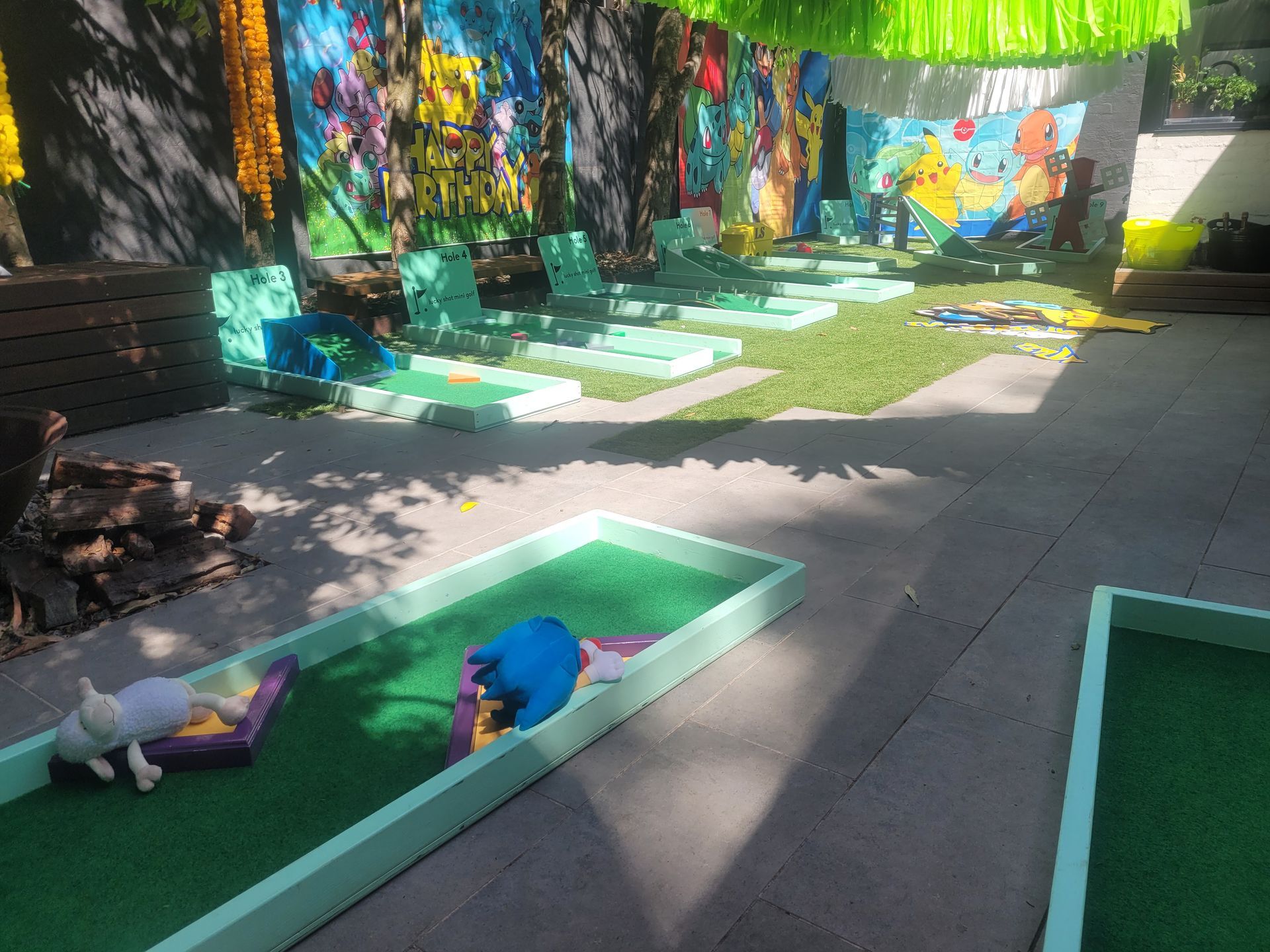 Miniature golf course with green turf and cartoon characters, rows of green lounge chairs in the background.