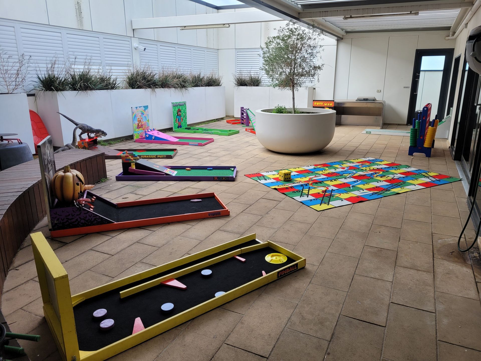 Miniature golf course in an enclosed patio, with various colorful obstacles and a puzzle mat.