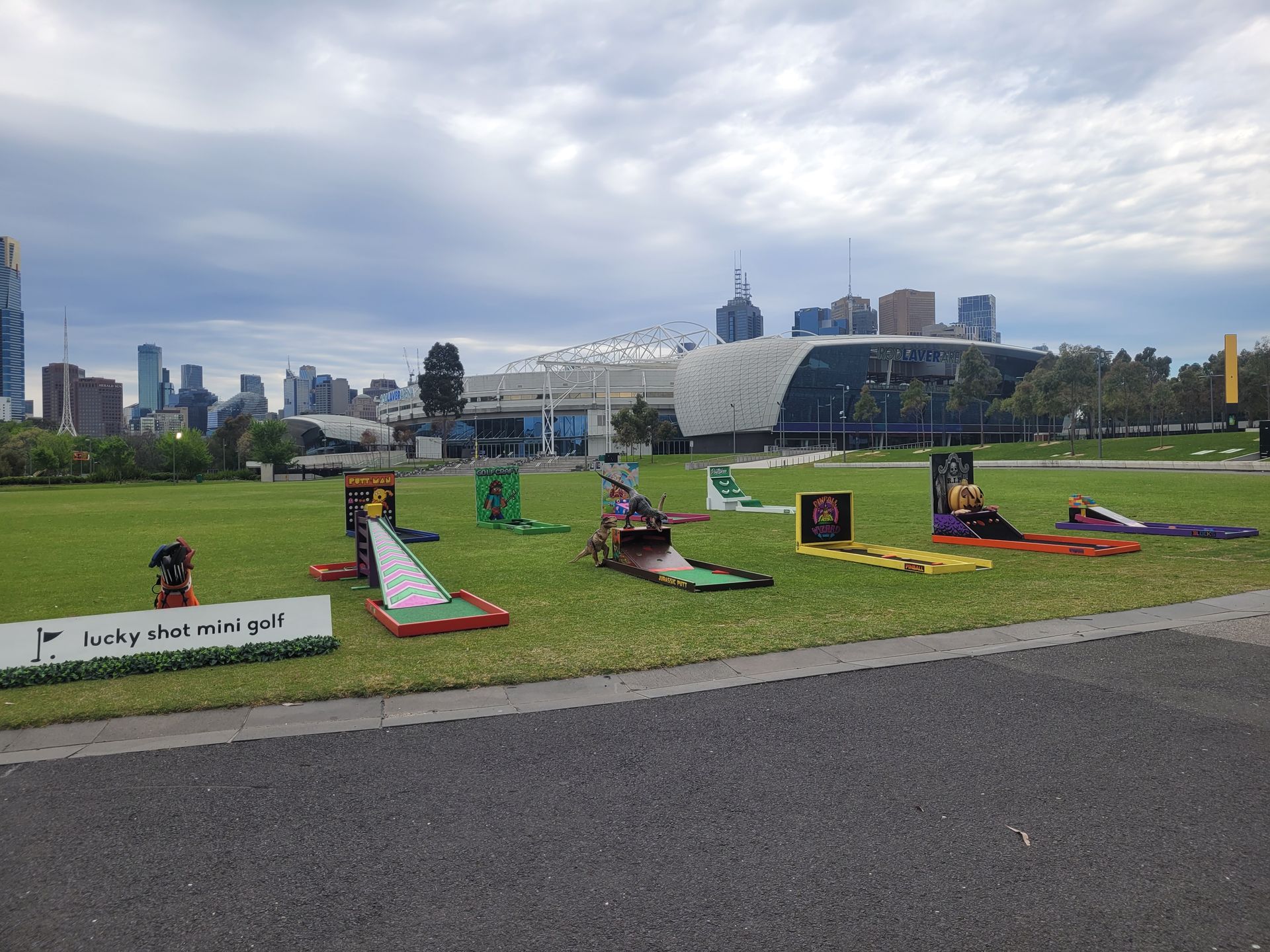 Miniature golf course set up outdoors with city skyline in the background.