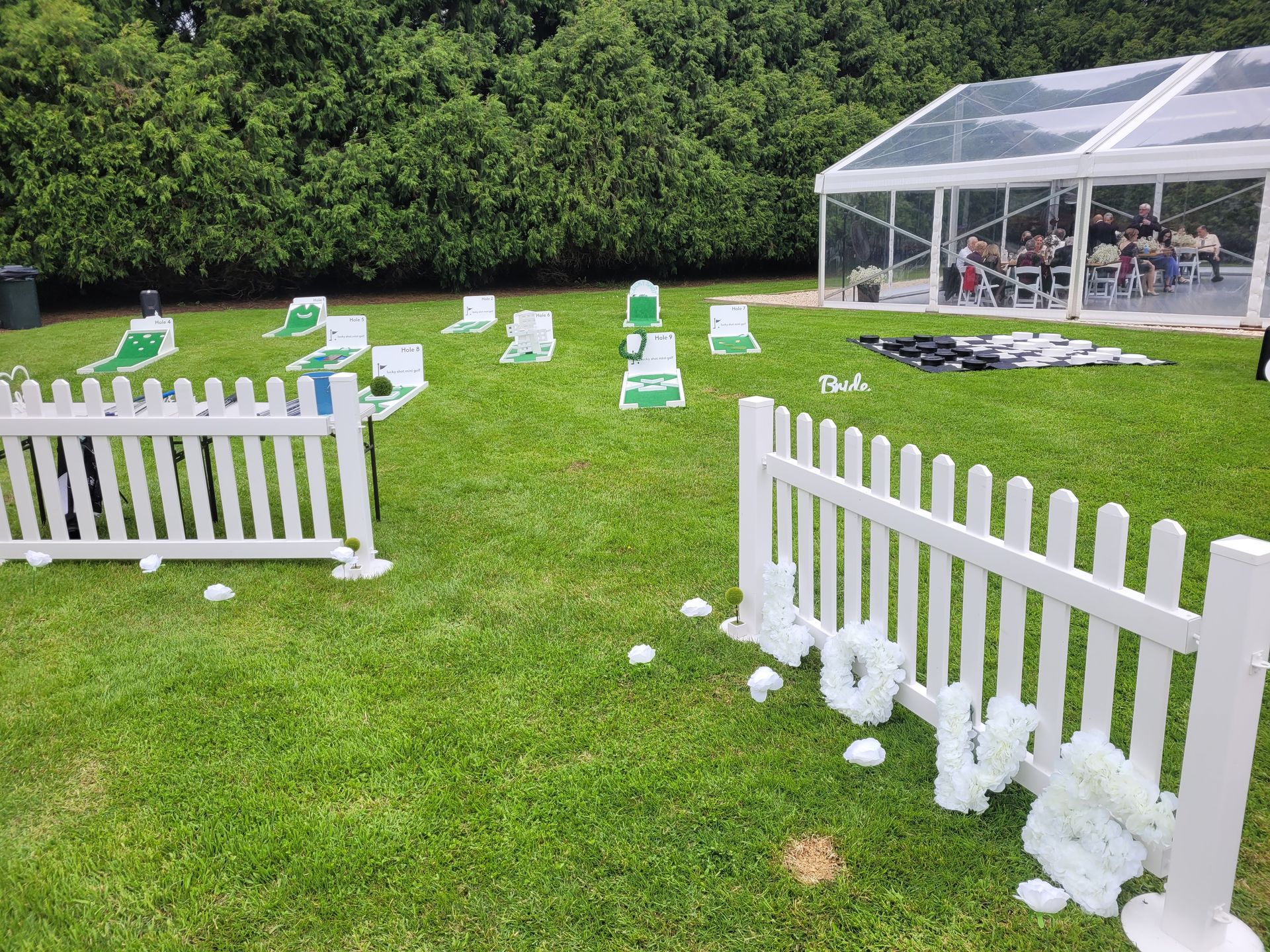 White picket fences, green lawn, event setup with tent and course.