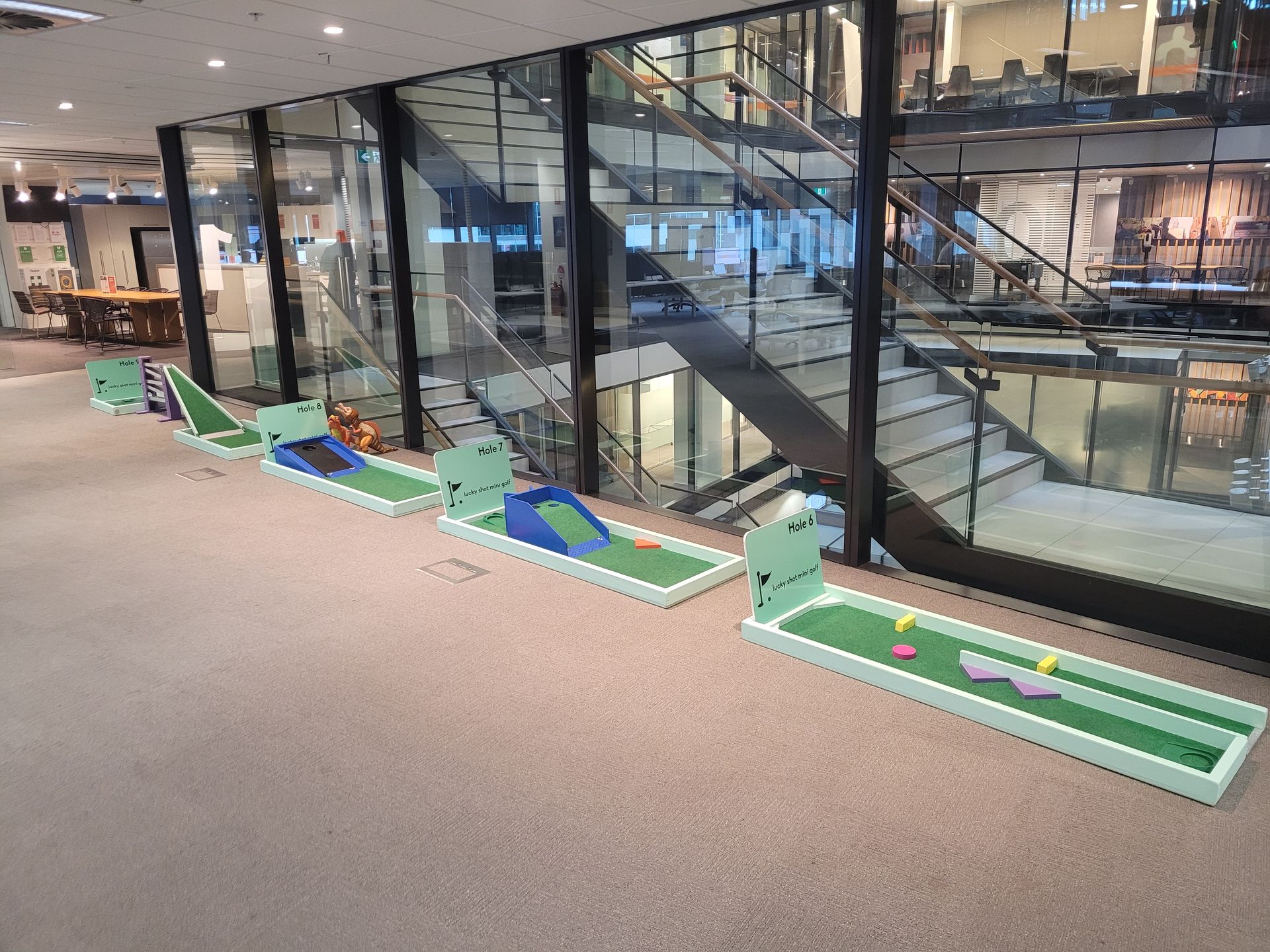 Miniature golf course set up on a grassy lawn, with a central gazebo and several putting greens.