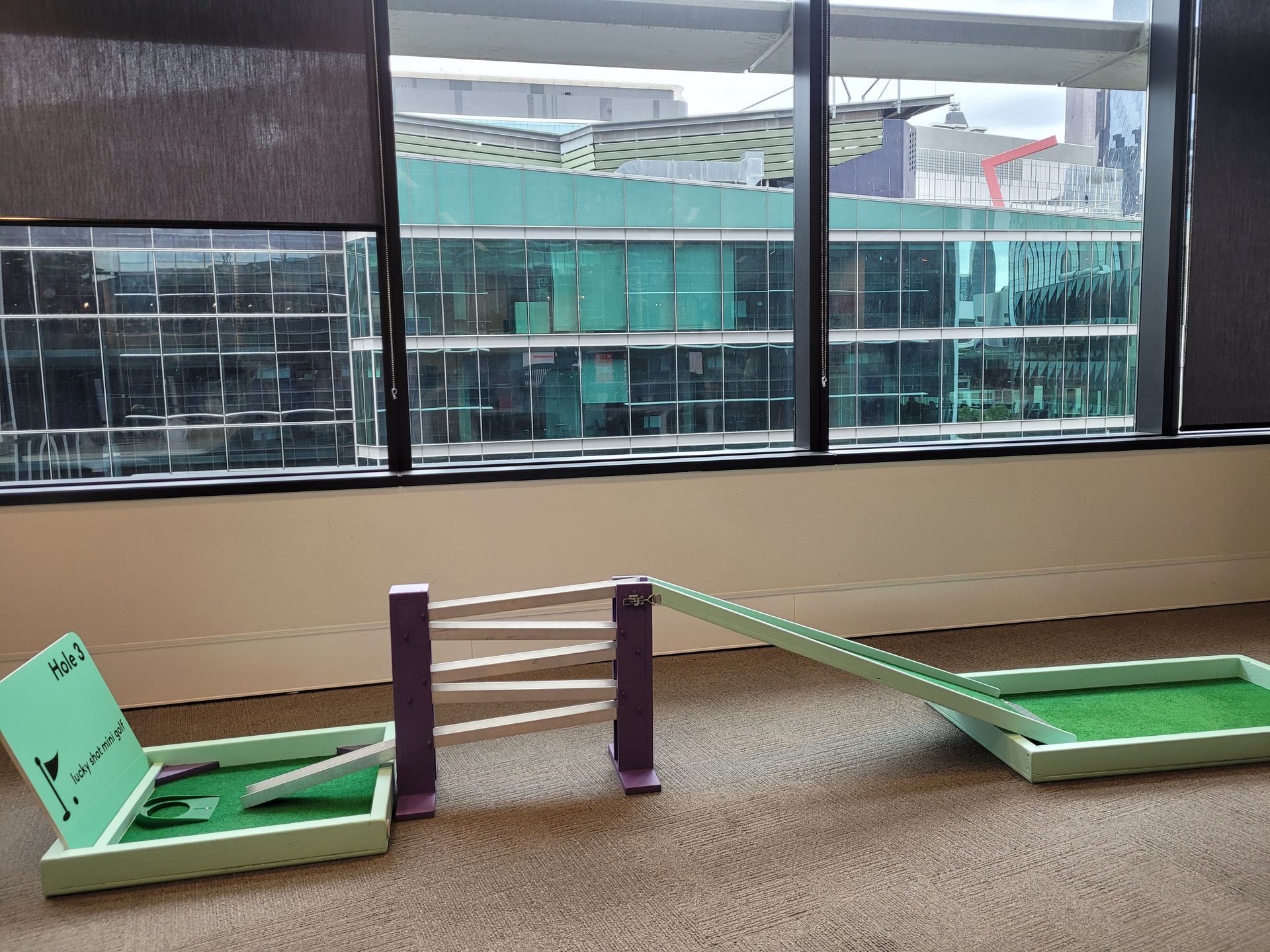 Miniature golf course set up on a grassy lawn, with a central gazebo and several putting greens.