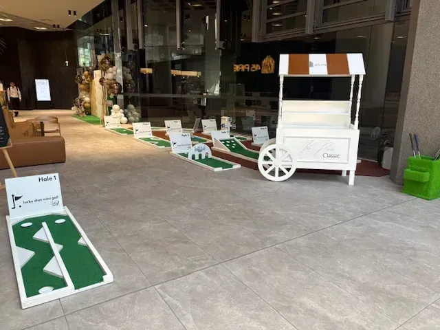 Arcade table with Pac-Man and Frogger screens, silver base, and joystick controls, on a white desk.
