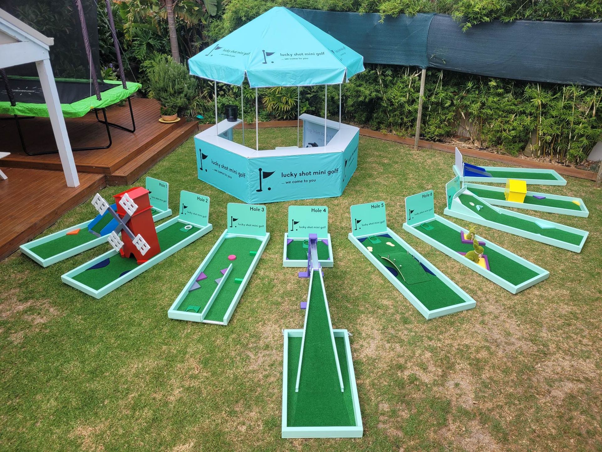 Miniature golf course set up on a grassy lawn, with a central gazebo and several putting greens.