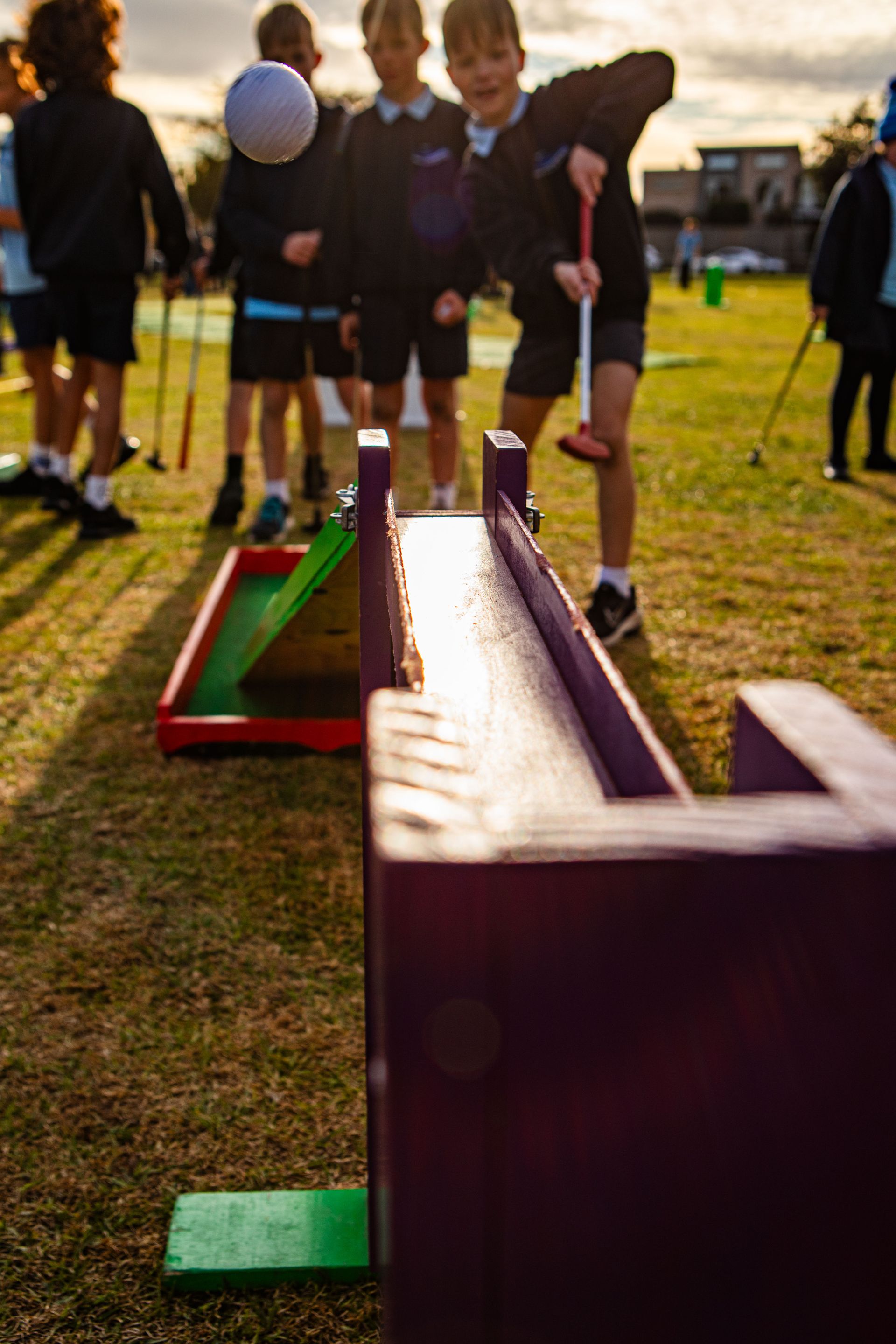 Person about to hit a golf ball on a miniature golf course with colorful zig-zag ramp.
