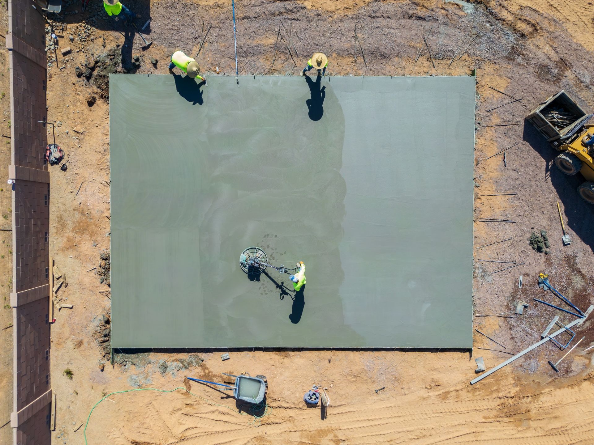 Overhead view of construction workers smoothing fresh concrete slab on a construction site.
