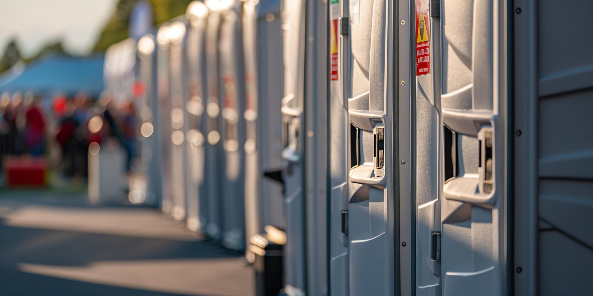 Row of portable restrooms lined up outdoors at an event. Row of portable restrooms lined up outdoors at an event.