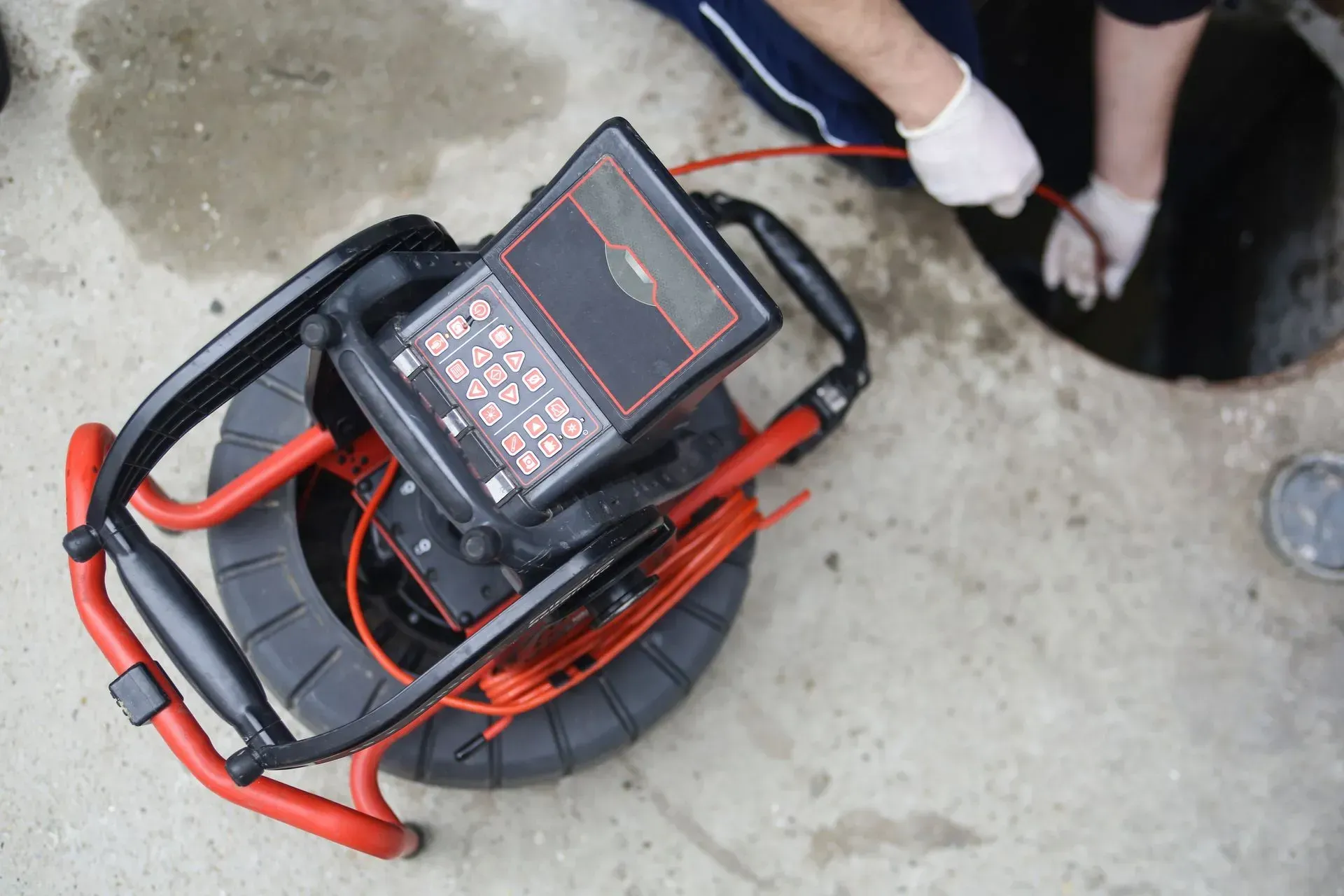 A person is using a camera to look into a manhole.