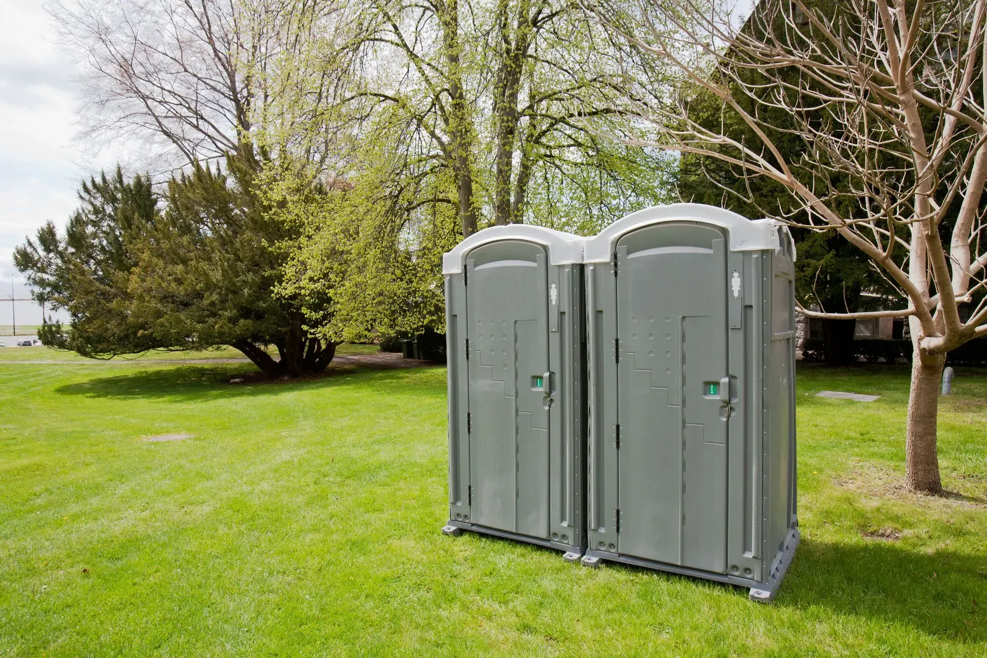 Two portable toilets are sitting on top of a lush green field.