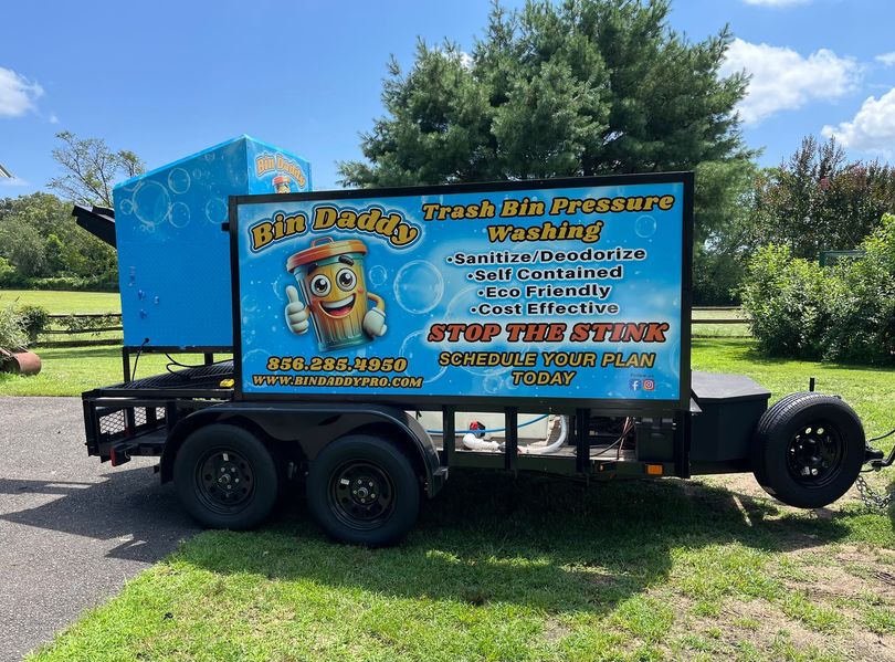 A trailer with a sign on it that says Bin Daddy trash bin pressure washing