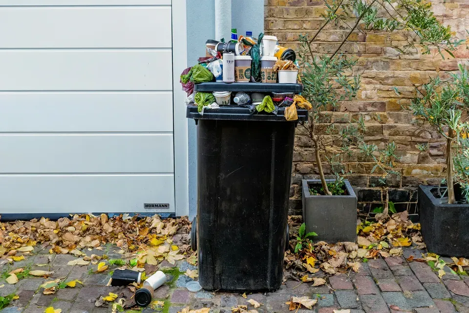 Bin Daddy Pro truck with cleaning equipment pressure washing a trash can outside