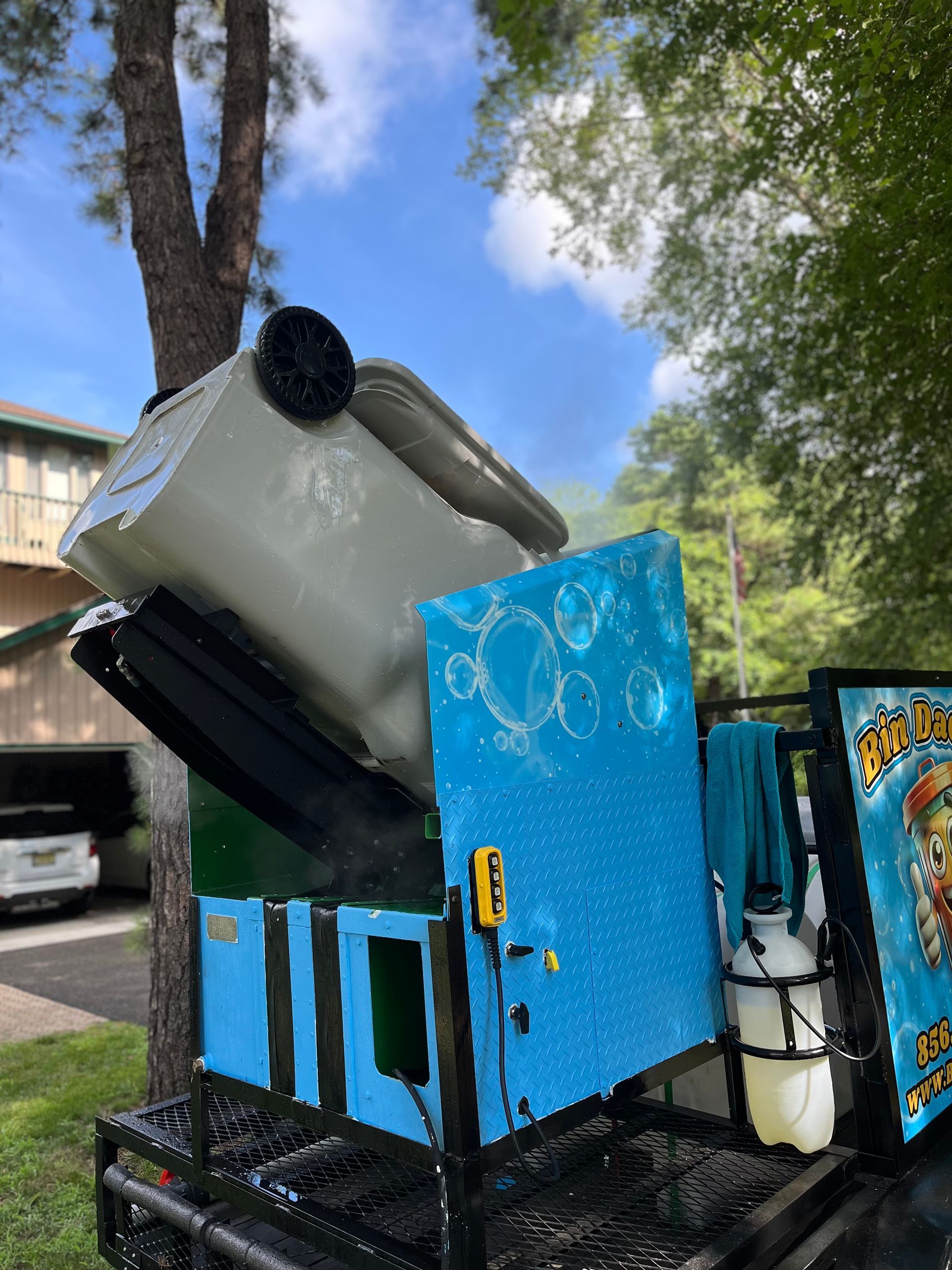 Grey trash bin upside down being cleaned and sanitized with Bin Daddy Pro pressure cleaning machine