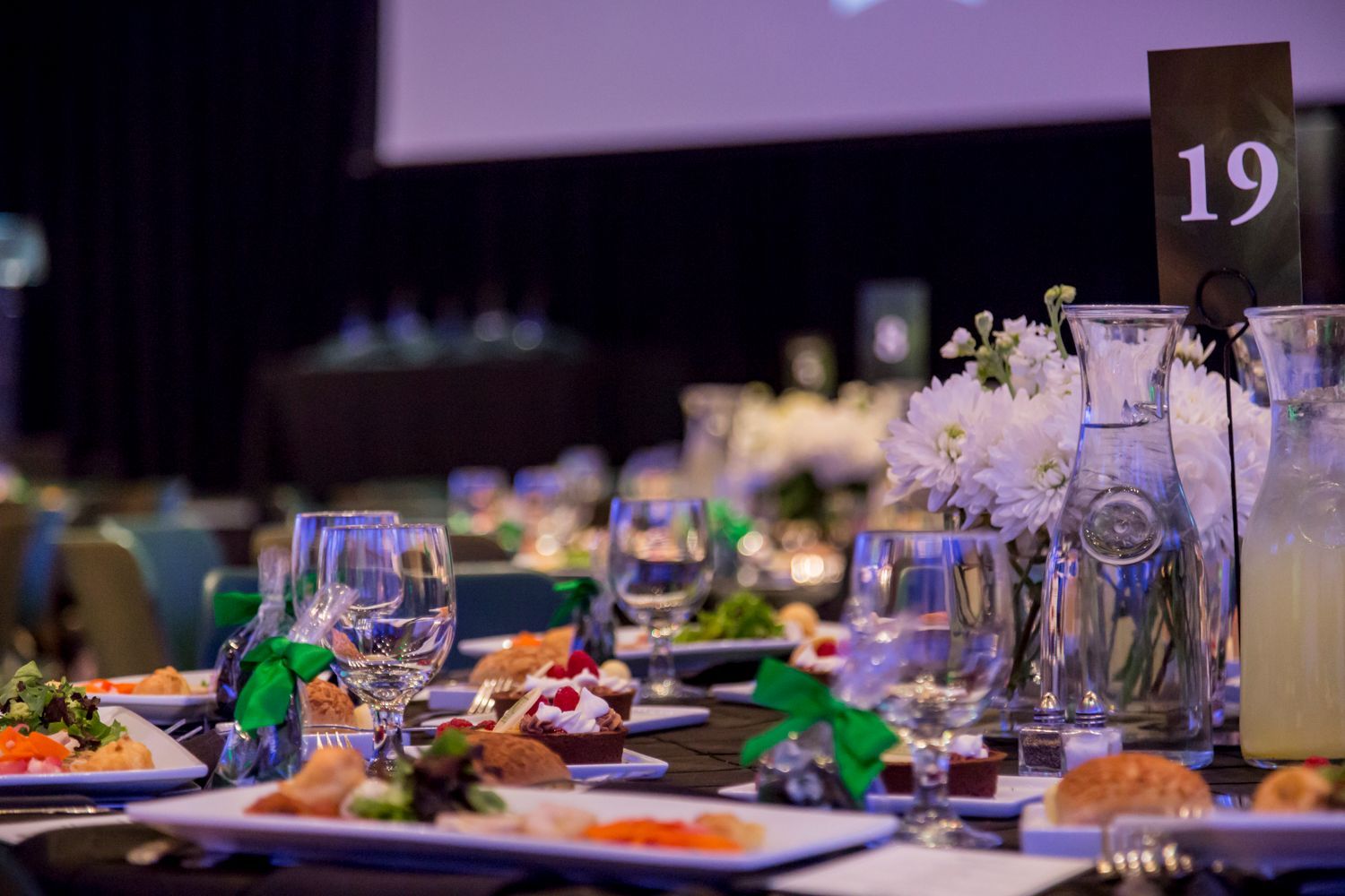 A table set for a dinner party with plates of food and glasses of wine.