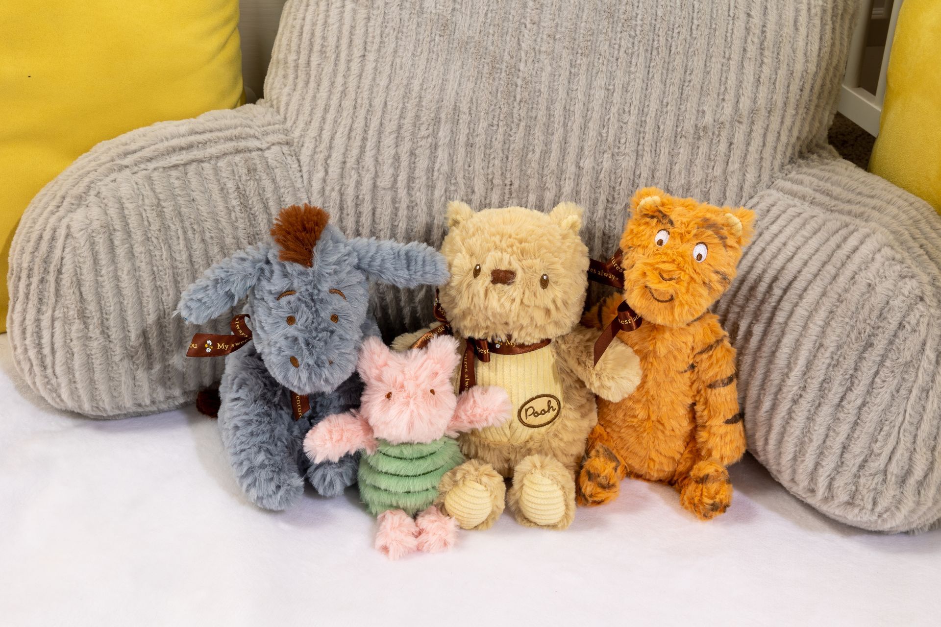 A group of stuffed animals sitting next to each other on a bed.