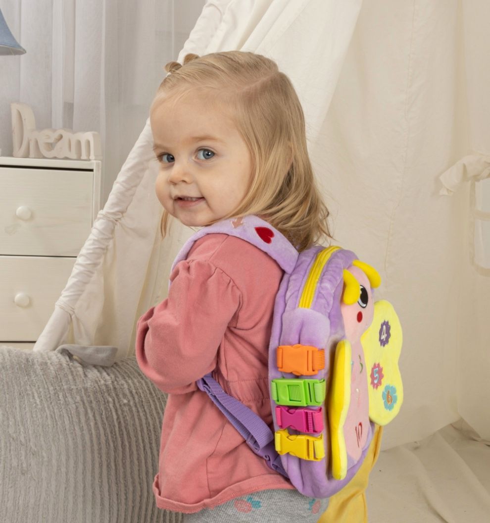 A little girl wearing a pink shirt and a purple backpack