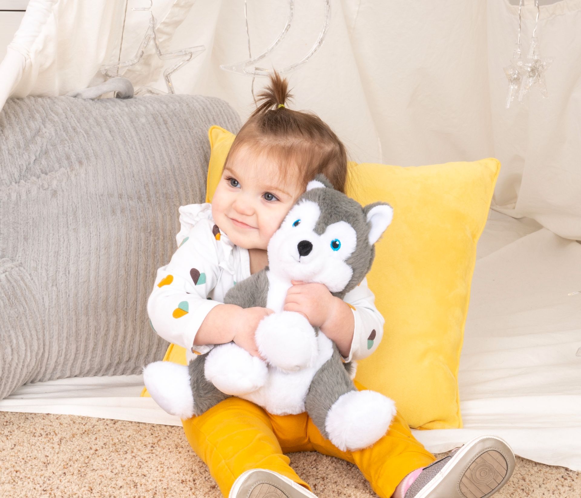 A little girl is sitting on the floor holding a stuffed animal.