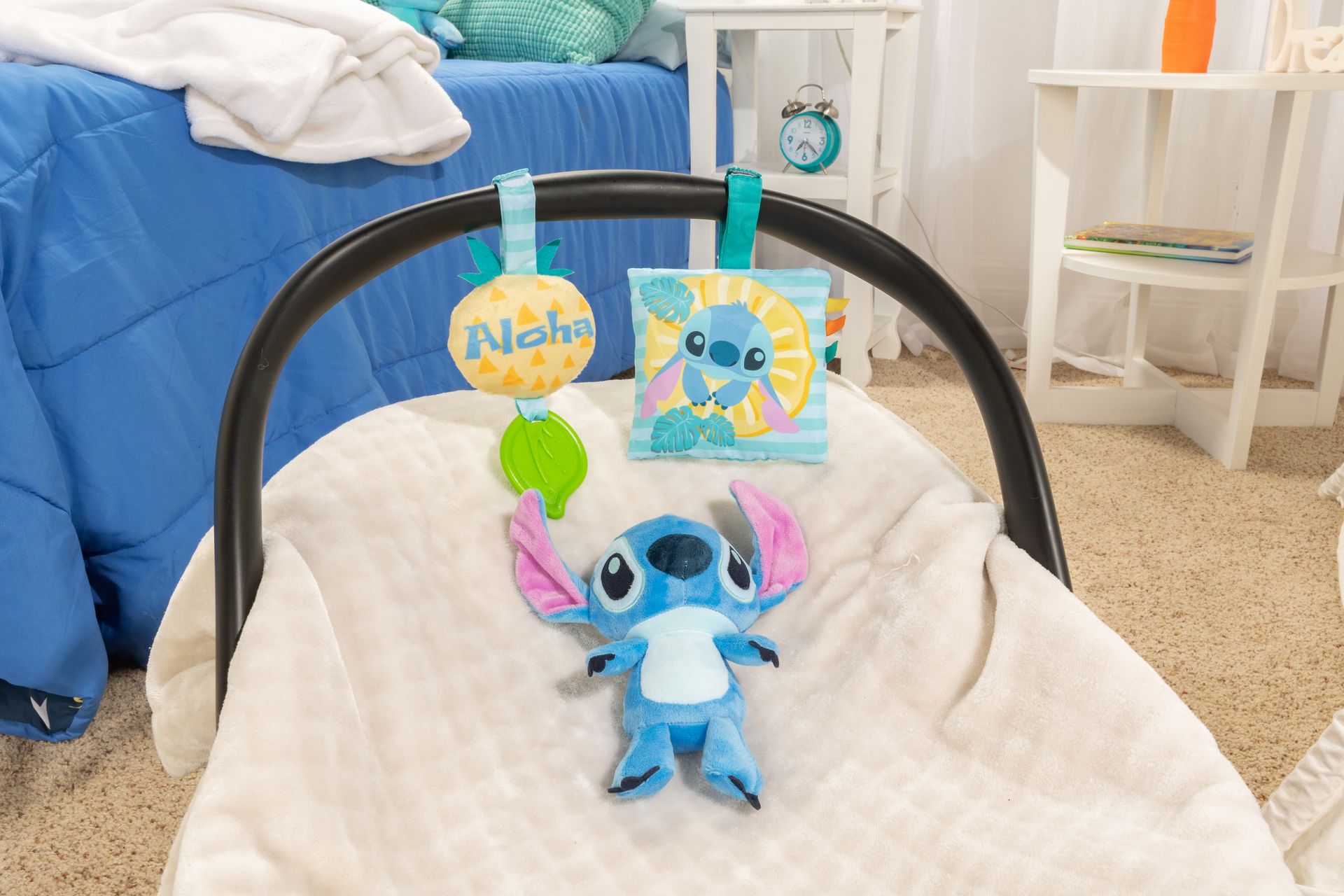 A baby car seat with a stitch toy attached to it.