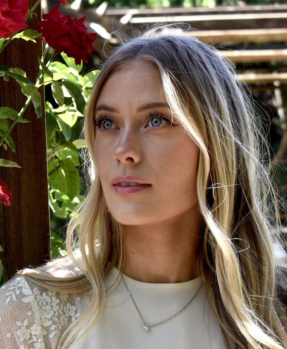 A close up of a woman wearing a necklace and earrings.