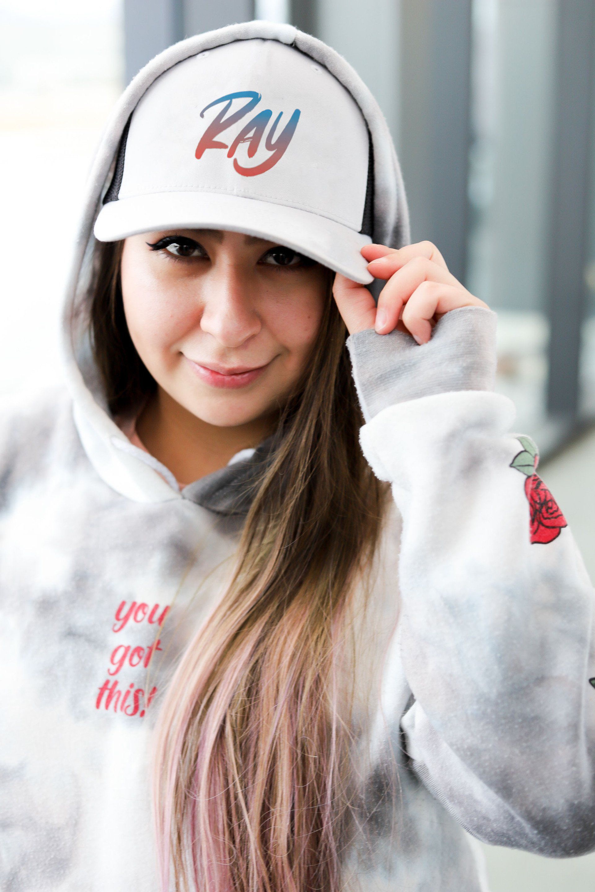 A woman wearing a hoodie and a hat with the word ray on it.