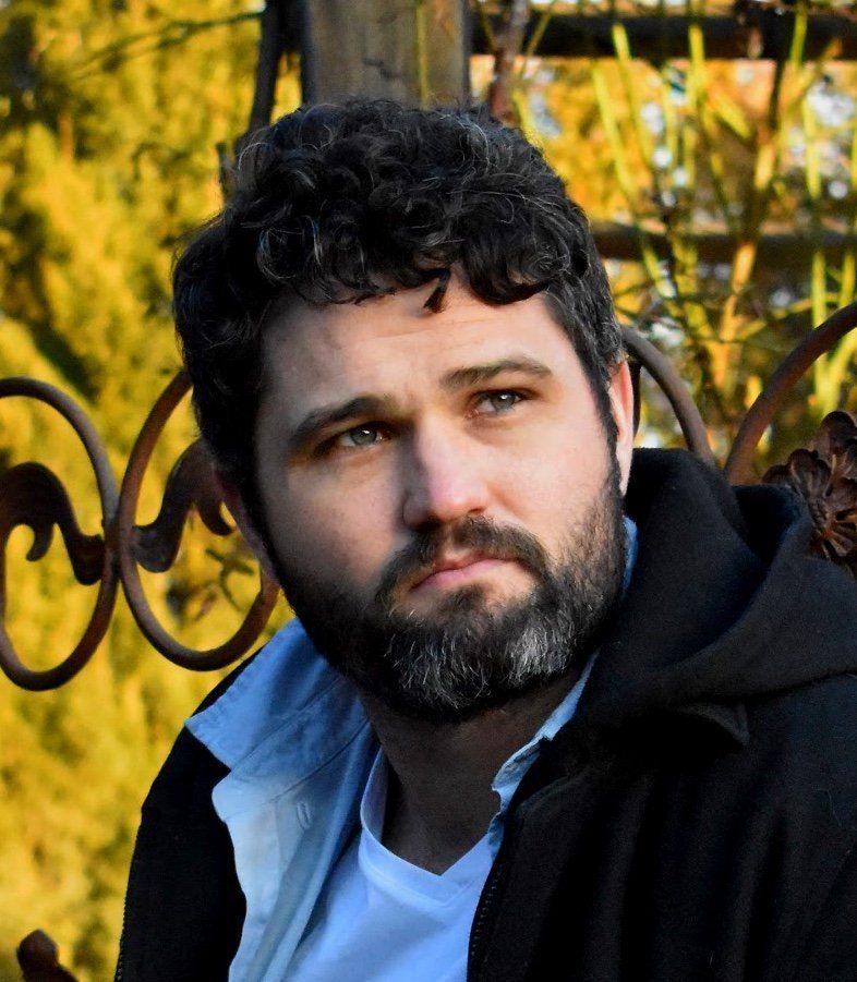 A man with a beard is wearing a black jacket