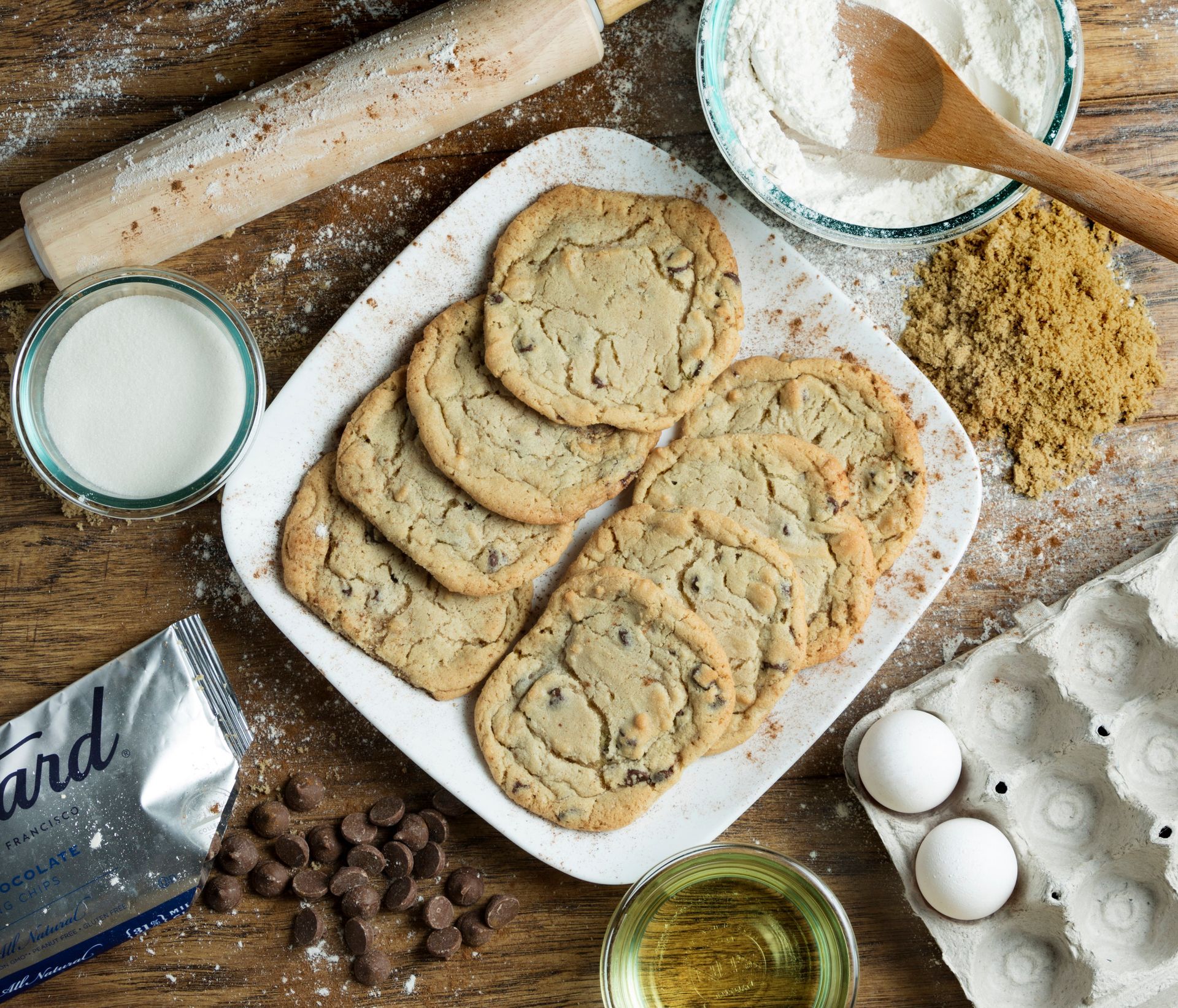 A white plate topped with chocolate chip cookies on a wooden table
