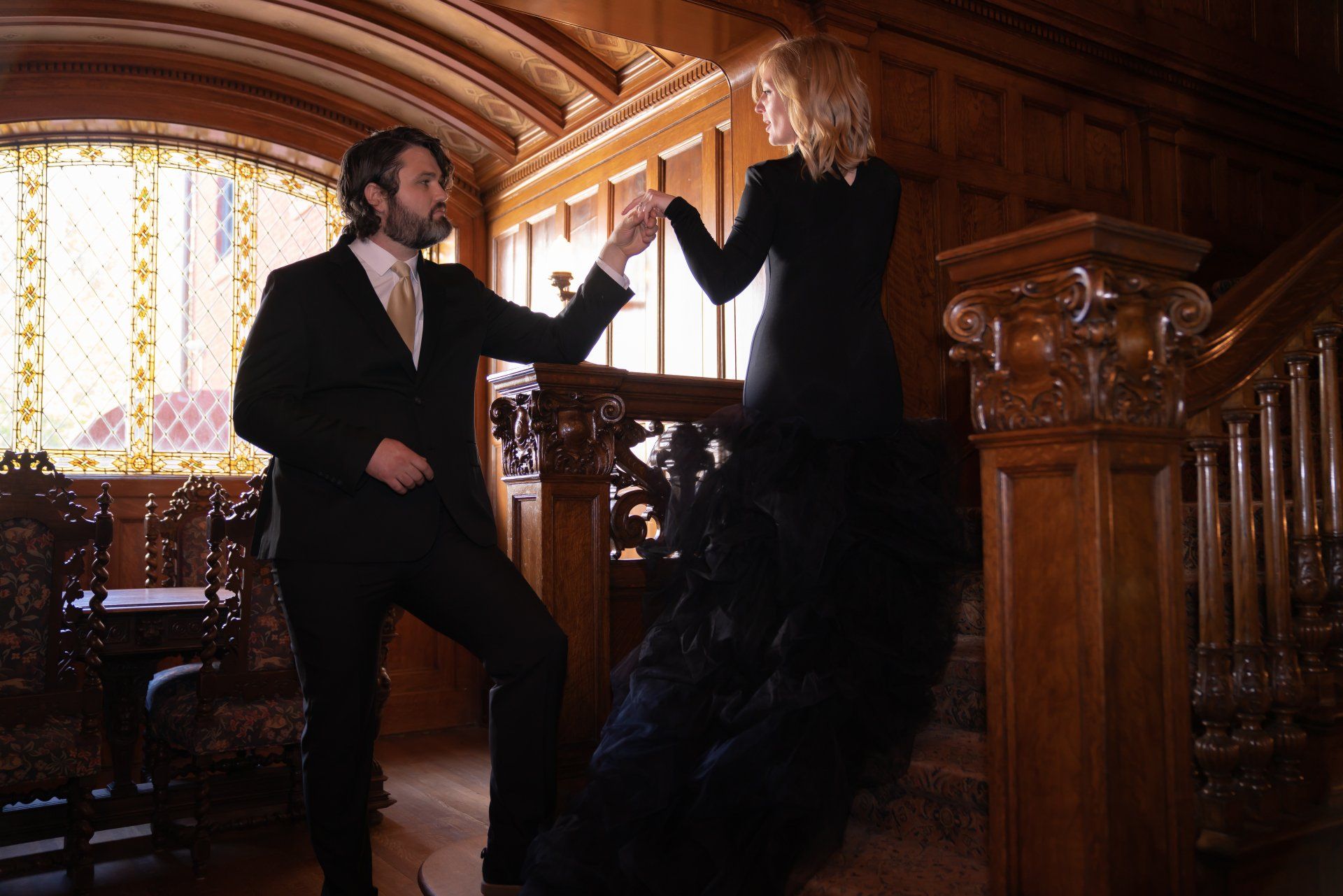 A man in a suit and tie is standing next to a woman in a black dress.