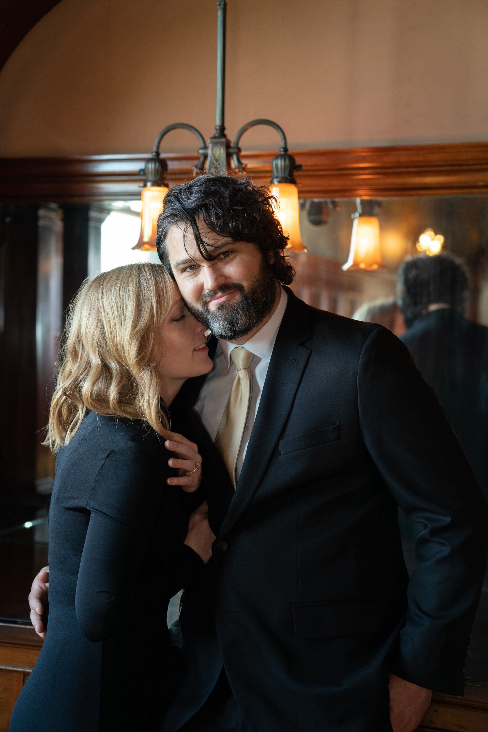 A man in a suit and tie is kissing a woman on the cheek.