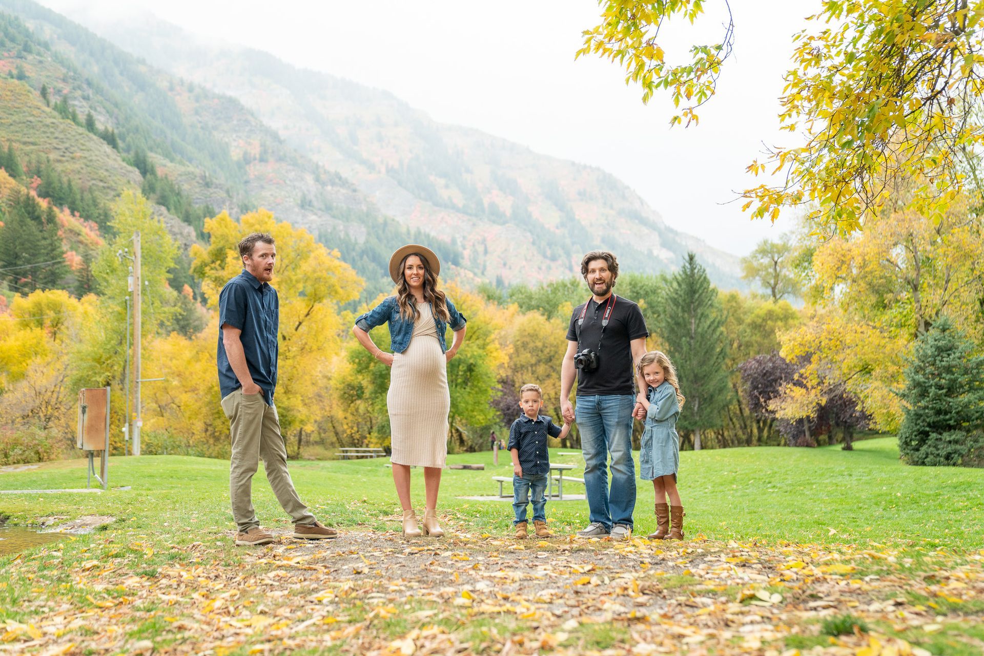 A family is standing in a park with mountains in the background.