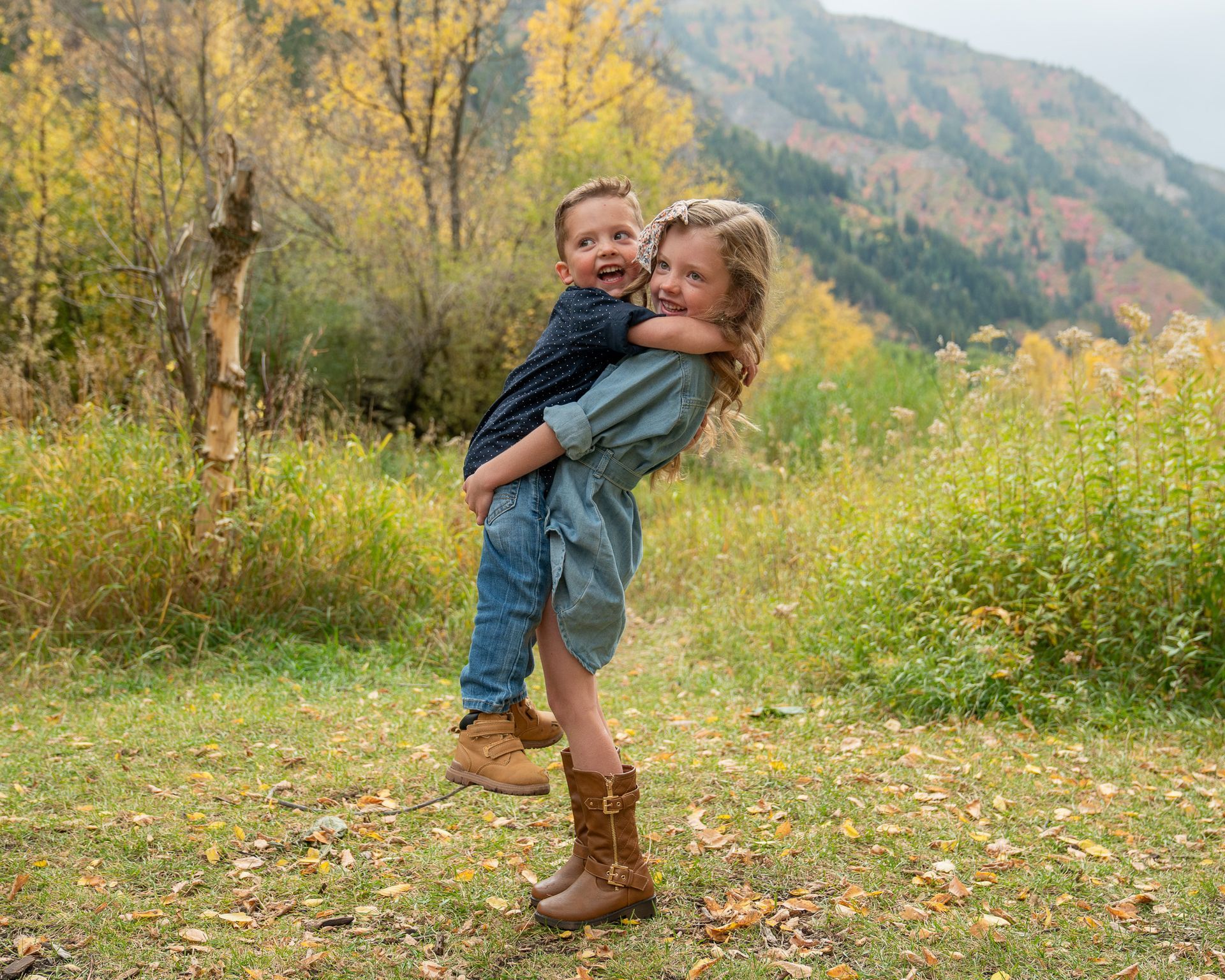 A girl is holding a boy in her arms in a field.