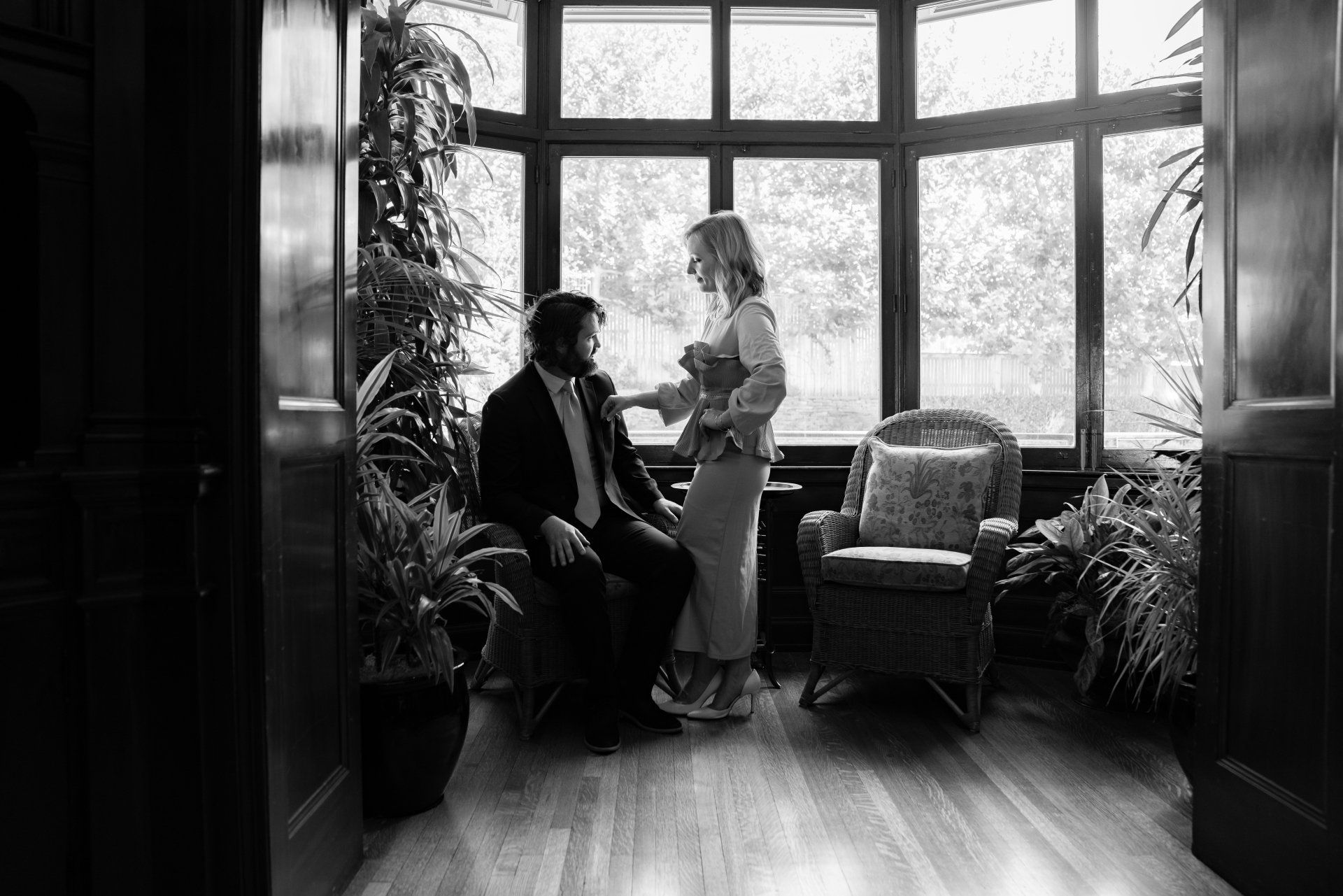 A black and white photo of a man and woman sitting in front of a window.