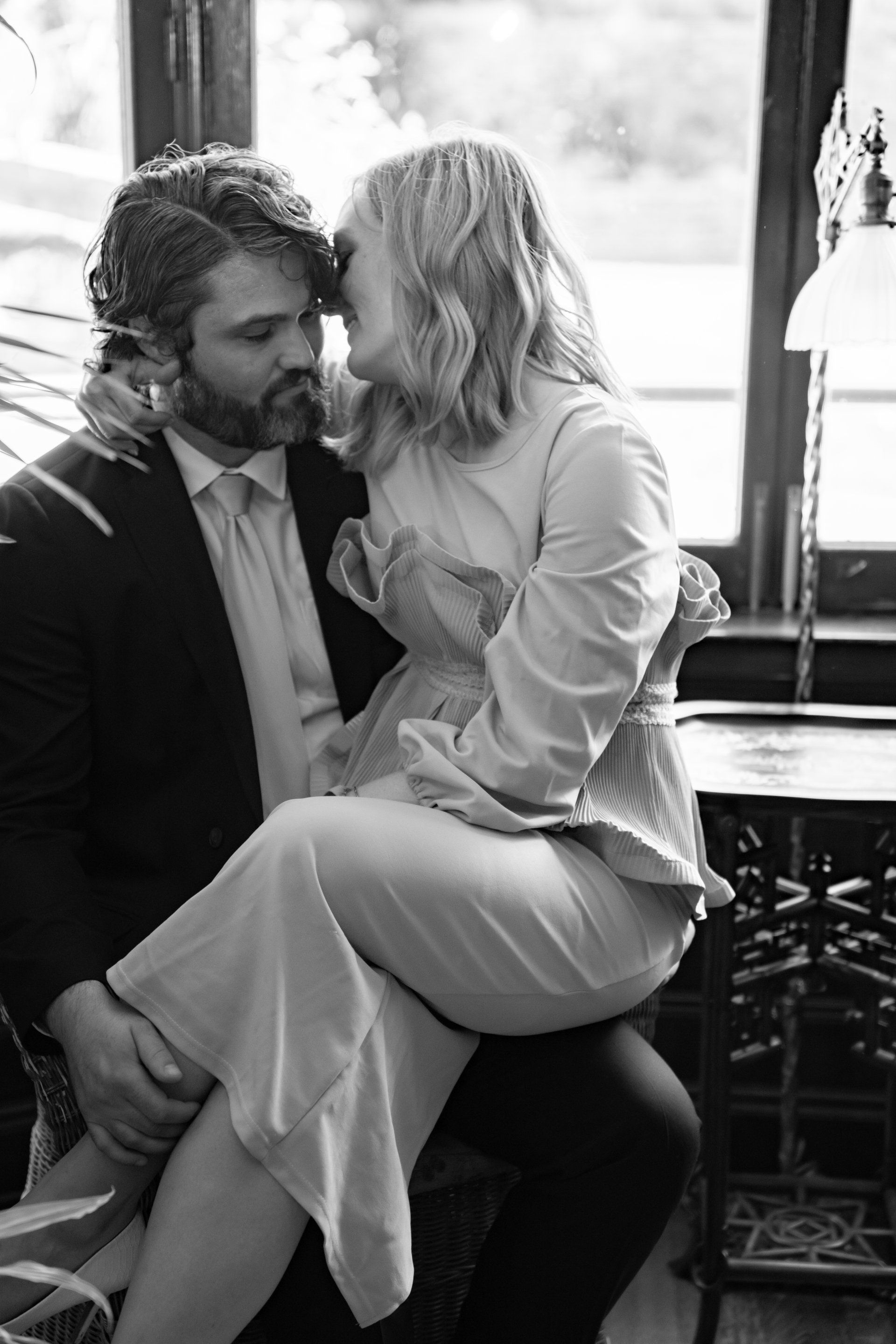 A black and white photo of a man carrying a woman on his lap.